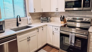 A modern kitchen with white cabinets, stainless steel appliances, a built-in microwave, and a toaster. - Camelback mountain condo with incredible views! Quick walk to the slopes!  (Tannersville)
