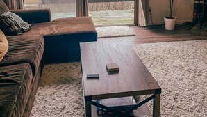 A cozy living room with a sofa, a coffee table, and a large sliding glass door leading to a balcony. - Camelback mountain condo with incredible views! Quick walk to the slopes!  (Tannersville)