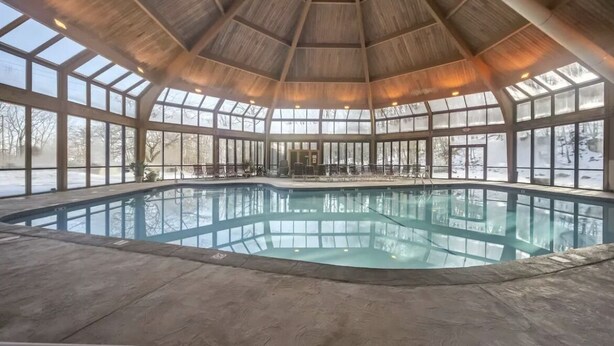 An indoor swimming pool with a wooden ceiling and large windows. - Camelback mountain condo with incredible views! Quick walk to the slopes!  (Tannersville)