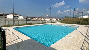 Una piscina rectangular con agua azul cristalina, rodeada por un solárium con baldosas.
