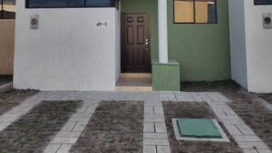 Un edificio residencial moderno con techo plano, puerta principal y garaje.