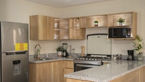 Una cocina moderna con armarios de madera, un refrigerador de acero inoxidable, una estufa a gas y un microondas.
