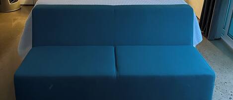 A bed with a white mattress and blue pillows, flanked by two bedside tables with lamps.