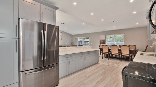 A modern kitchen with stainless steel appliances, a large island, and a dining area with chairs. - Spacious 4 bedrooms, 2 bathroom house with pool (Miramar)