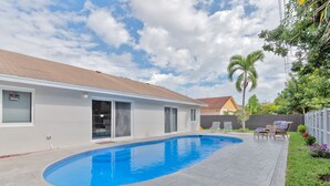 A residential backyard with a swimming pool, a covered patio, and a fenced area with outdoor furniture. - Spacious 4 bedrooms, 2 bathroom house with pool (Miramar)