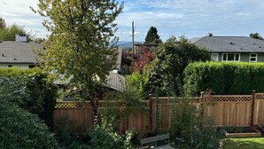 Ein Garten mit Holzzaun, einer Bank und verschiedenen Pflanzen.