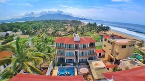 A beachfront hotel with multiple balconies, a swimming pool, and a view of the ocean. - Hotel Casa Shula Acapulco (Coyuca de Benitez)