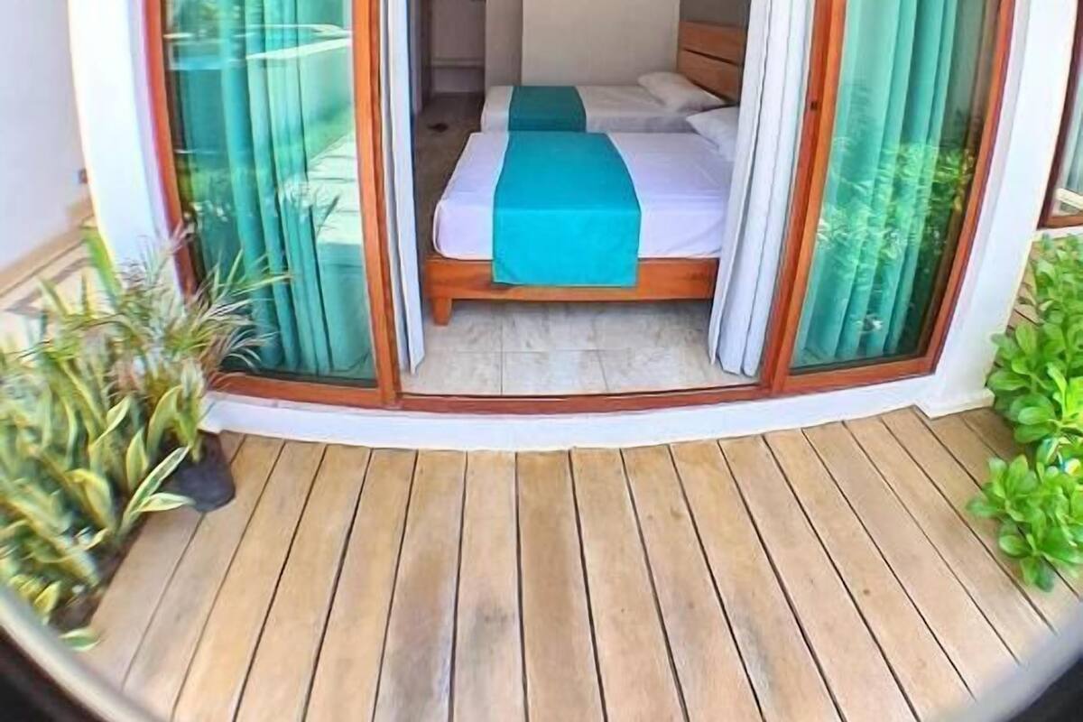 Un dormitorio con cama, cortinas y suelo de madera.