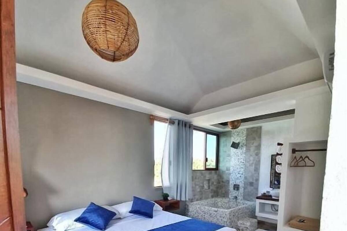 Un dormitorio con una cama grande, una pared de piedra y un baño pequeño.