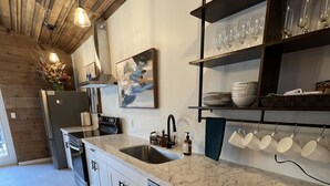A modern kitchen with white cabinets, stainless steel appliances, and a marble countertop. - Vintage Roost at Fleming Farms (Lincoln)