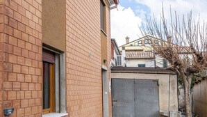 Un edificio de ladrillo con una puerta entrecerrada, una ventana y un contador eléctrico a la vista.
