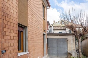 Un edificio de ladrillo con una puerta entrecerrada, una ventana y un contador eléctrico a la vista.