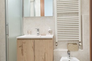 A bathroom with a wooden vanity, a mirror, a sink, and a towel rack.