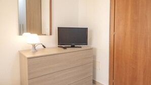 Un aparador de madera con un televisor de pantalla plana, una lámpara y un espejo encima.