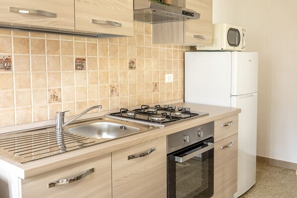 Una cocina equipada con estufa, lavaplatos, horno y microondas.