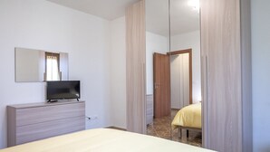 Un dormitorio con cama, televisor en una cómoda y un espejo.