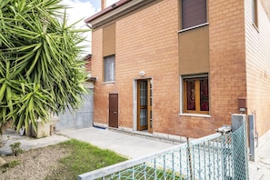 Un bâtiment à deux étages, construit en briques, avec une porte d’entrée, une petite fenêtre et une boîte aux lettres bien visible.