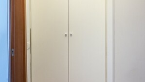 Un armario blanco cerrado con dos pomos, un marco de puerta de madera y una pared blanca.