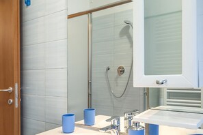 Un baño con ducha, lavamanos y espejo.