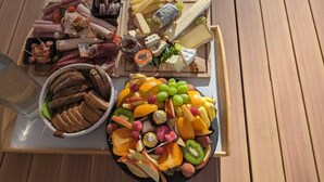 A wooden table with a variety of cheeses, cured meats, and fruits. - Studio Romantique Indépendant Avec Jacuzzi (Saint-Andiol)