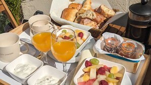 A breakfast tray with croissants, fruit, yogurt, and orange juice on a wooden table outdoors. - Studio Romantique Indépendant Avec Jacuzzi (Saint-Andiol)