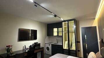 A modern bedroom with a bed, desk, and built-in washer-dryer.