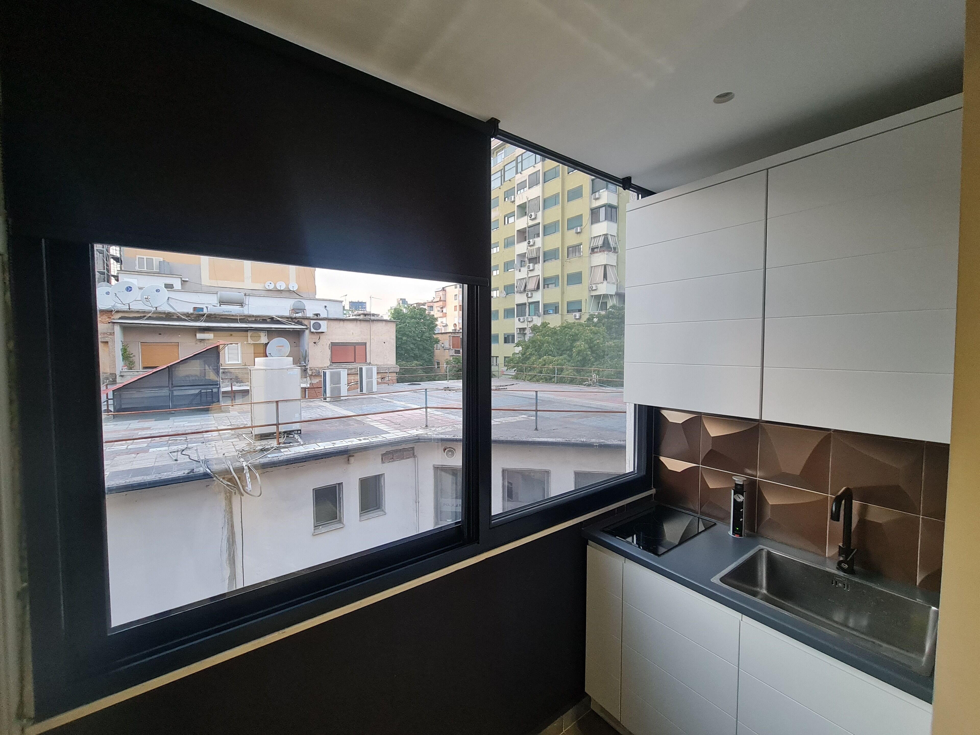 Una cocina moderna con un ventanal amplio, armarios blancos y vista a una zona residencial.