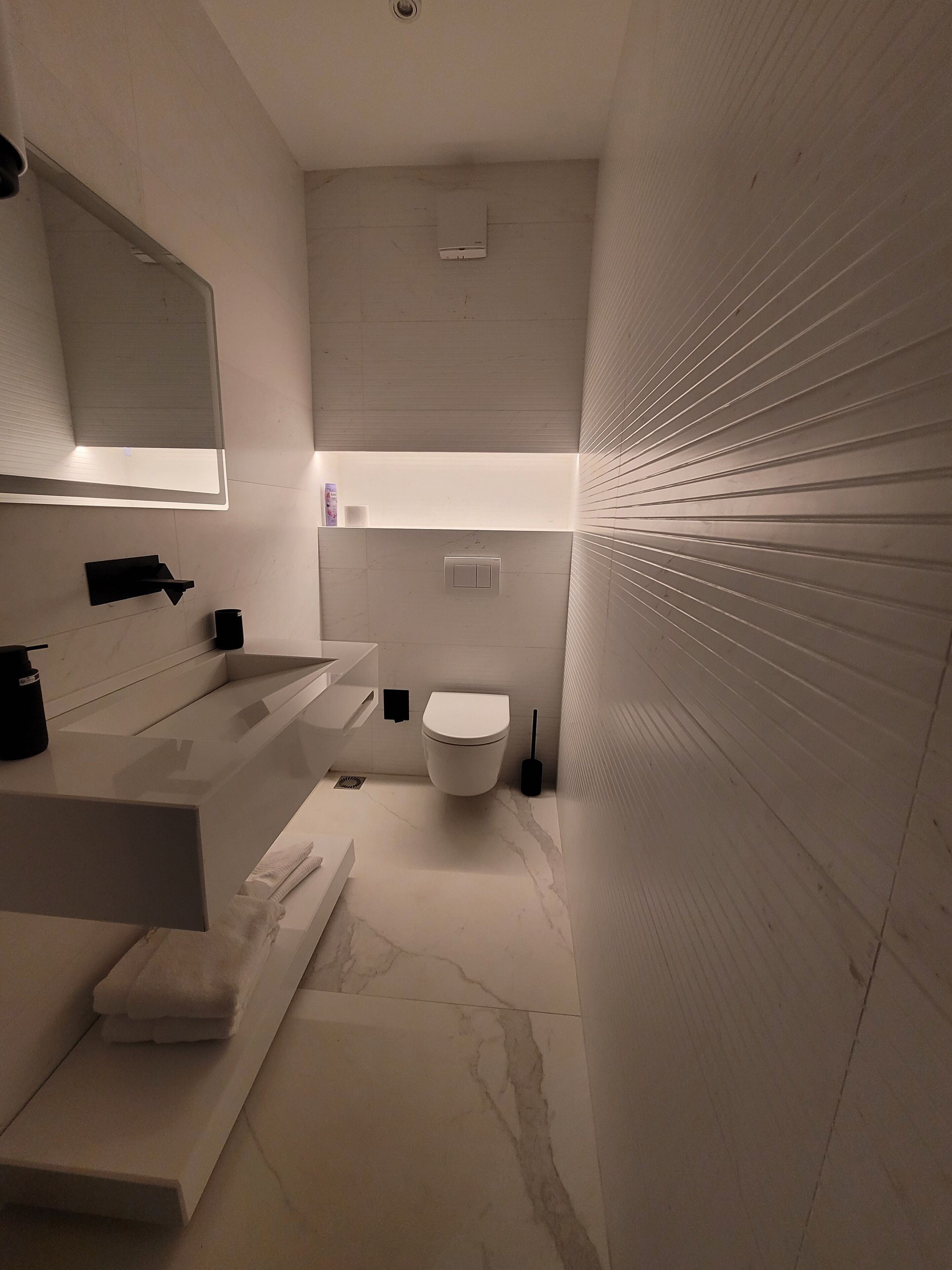 A modern bathroom with a white sink, mirror, and toilet.