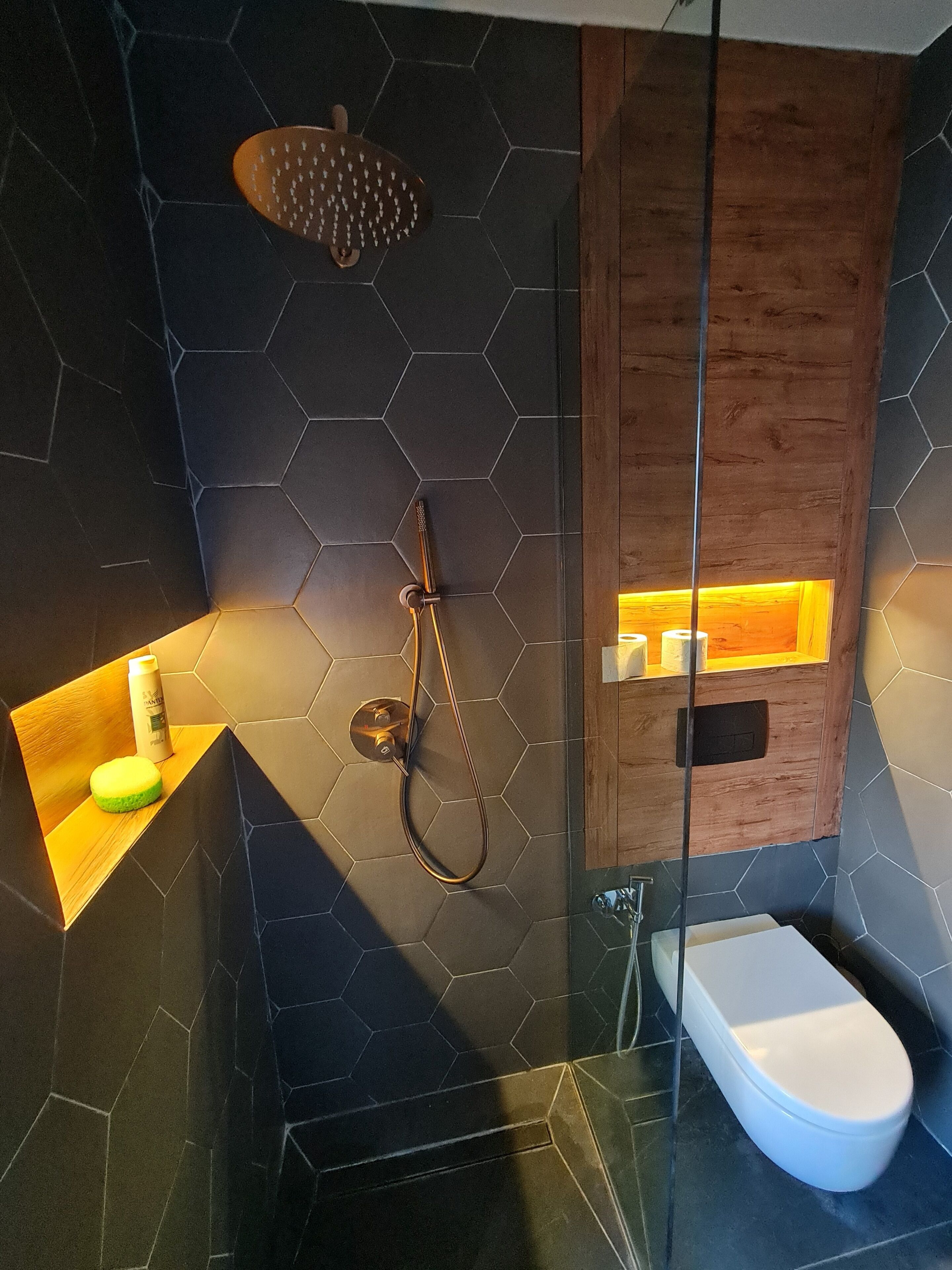 Une salle de bain moderne équipée d’une douche, de toilettes et d’un meuble-lavabo avec un distributeur de savon.