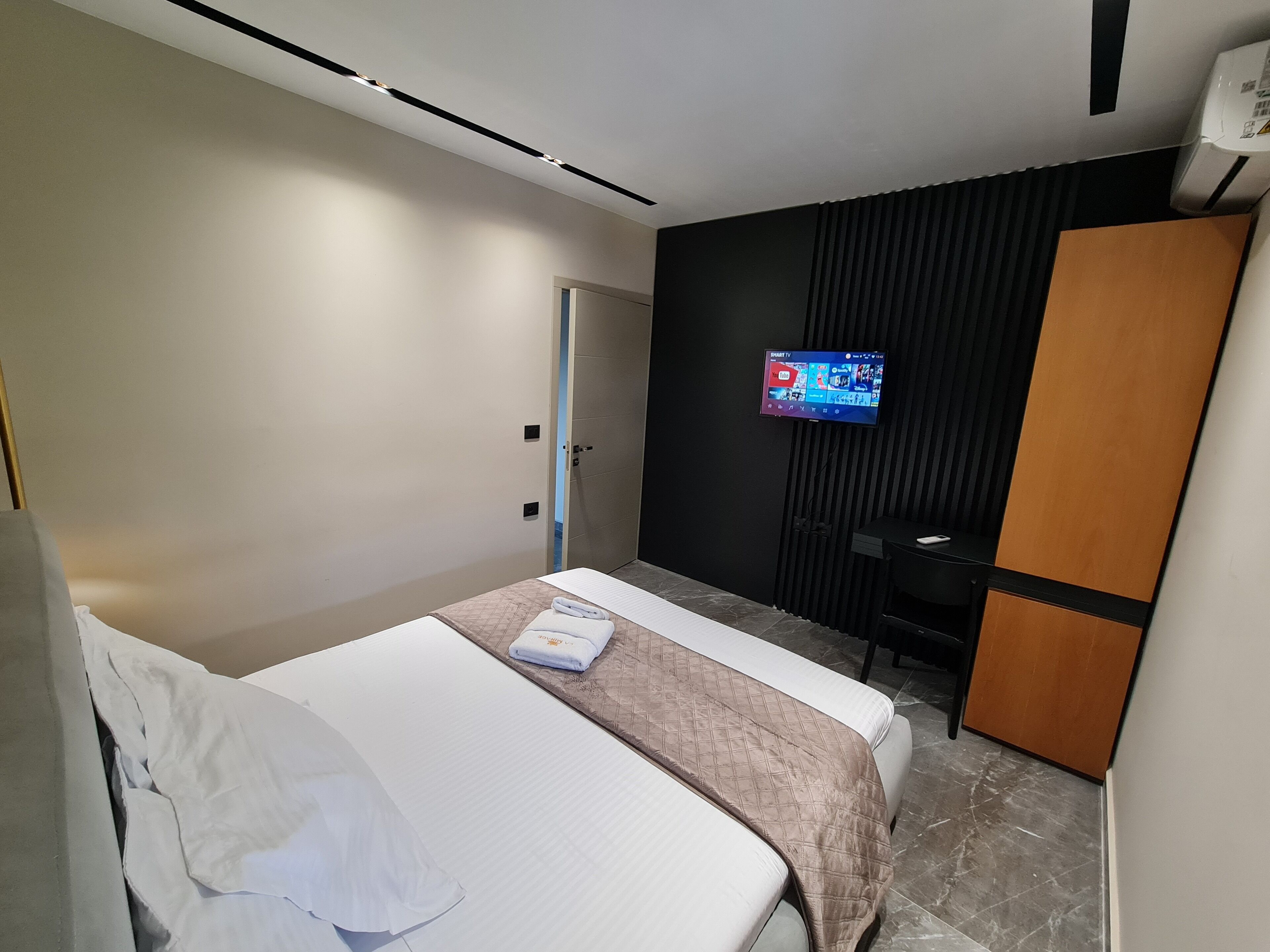 Une chambre d’hôtel moderne équipée d’un lit, d’un téléviseur fixé au mur et d’une armoire.