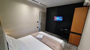 Une chambre d’hôtel moderne équipée d’un lit, d’un téléviseur fixé au mur et d’une armoire.