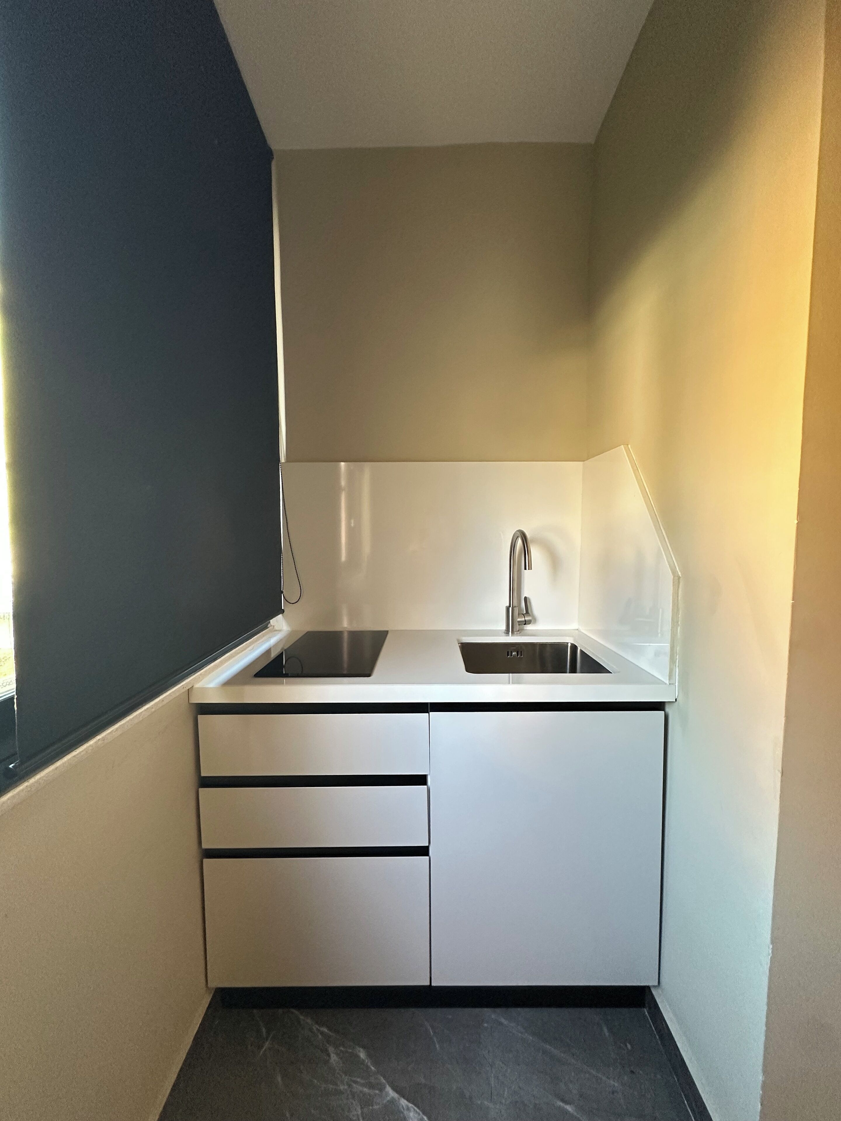 A compact kitchen with a double sink, a faucet, and a countertop.