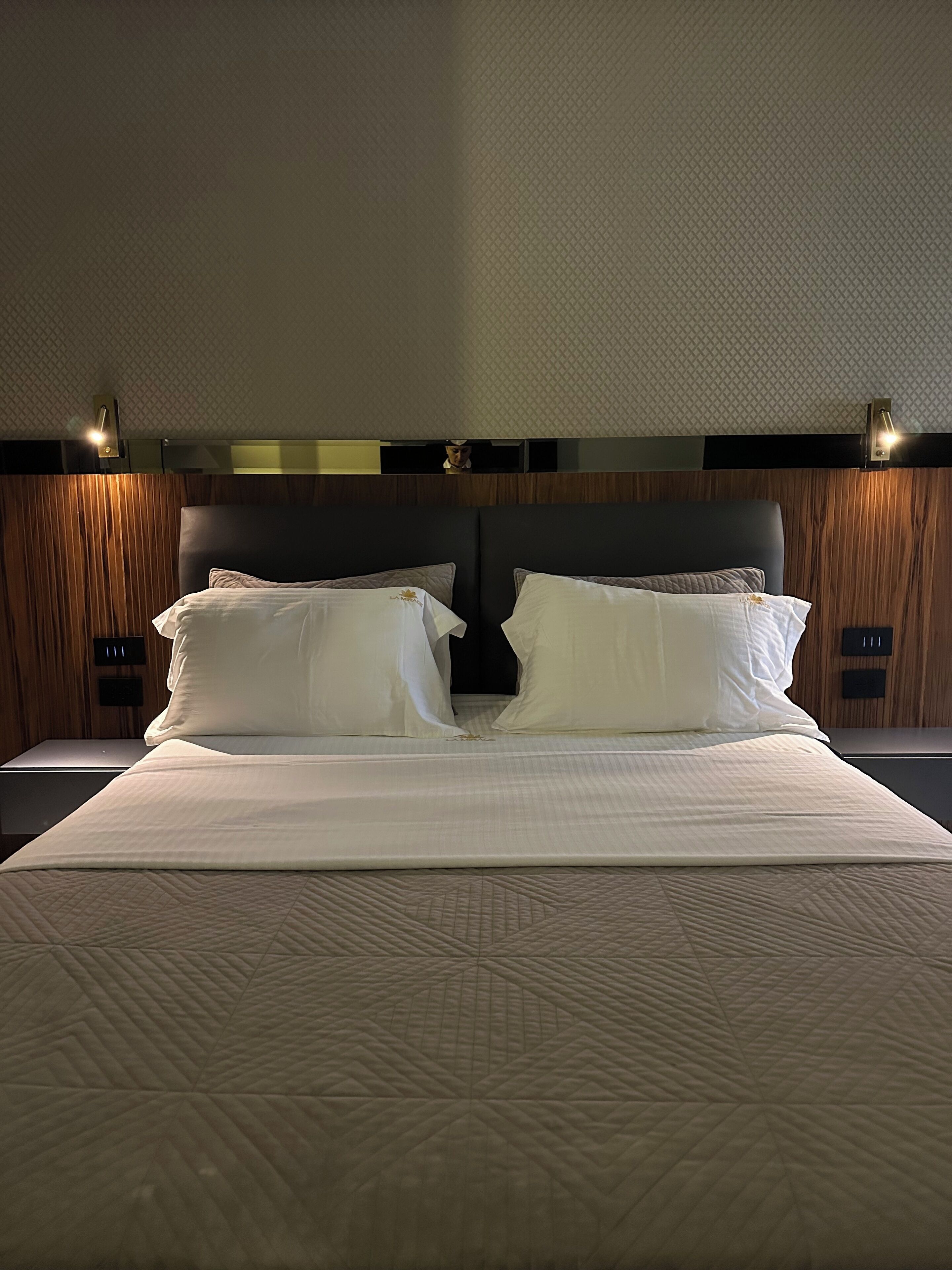 Une chambre d’hôtel avec un grand lit, deux tables de chevet et une tête de lit en bois.