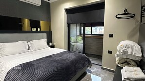 Un dormitorio moderno con una cama grande, cabecera negra, aire acondicionado mural y ventana con vistas.