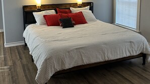 A bedroom with a wooden bed, white bedding, and two bedside lamps. - The House on East Main: 5 mins to downtown and 5 mins to SFA University (Nacogdoches)