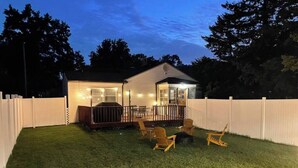Una casa con patio trasero cercado, un porche cubierto y mobiliario exterior.