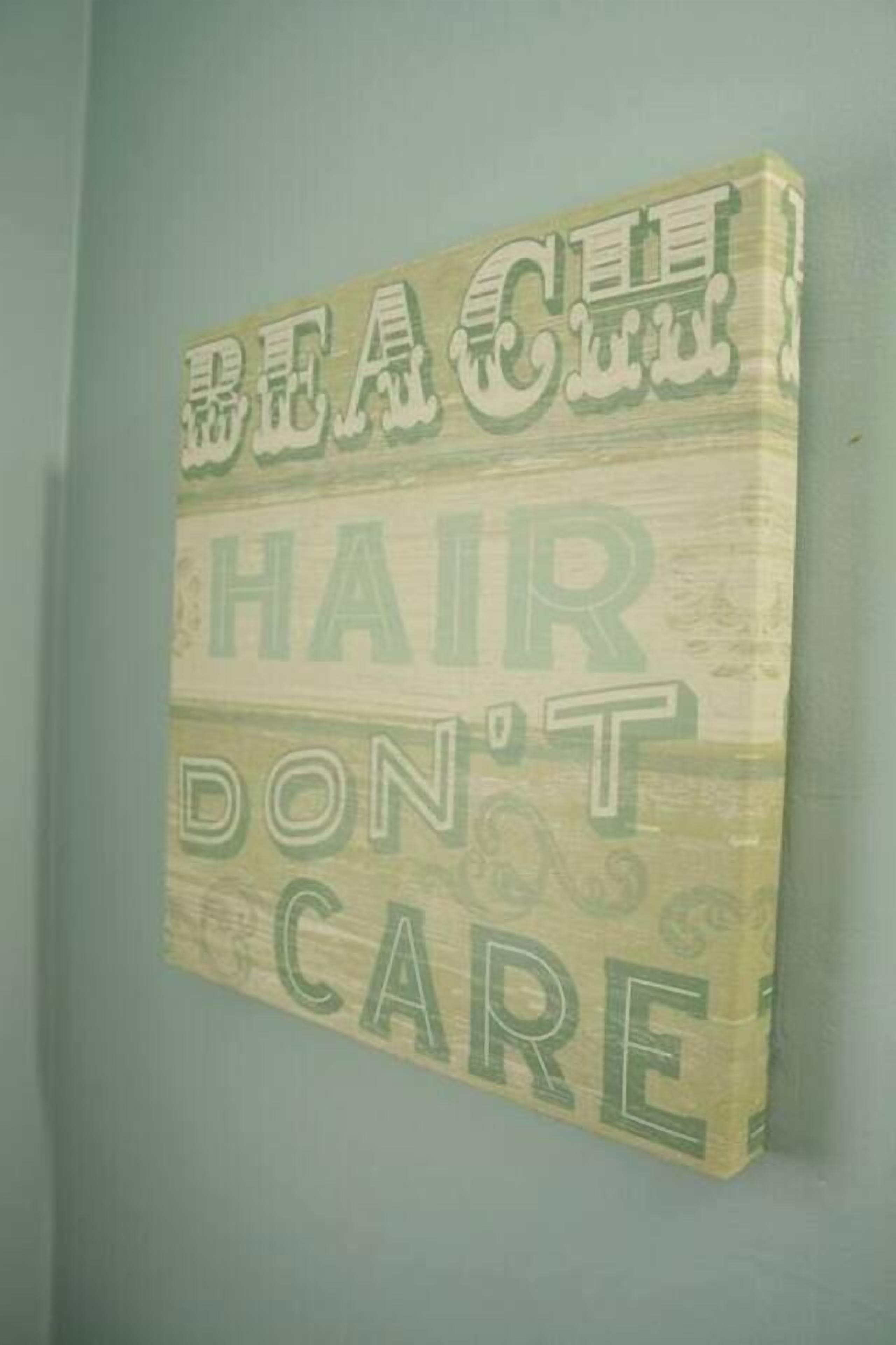 Una pared con un letrero que dice 'BEACH HAIR DON'T CARE' en letras grandes.