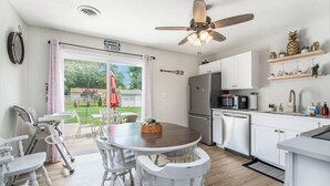 A modern kitchen with a dining area, a ceiling fan, and a view of the backyard.