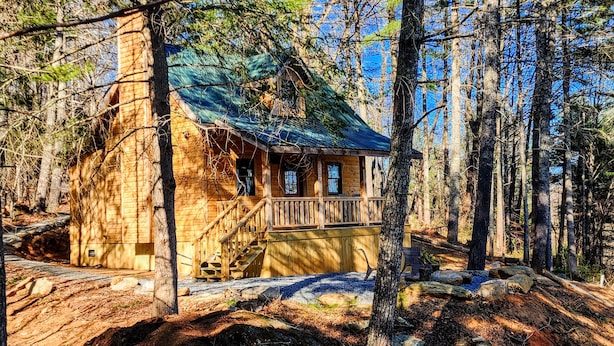 Eine rustikale Holzhütte mit Veranda und einer Treppe zum Eingang.
