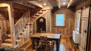 Ein rustikales Holzinterieur mit einer Holztreppe, einem Esstisch mit Stühlen und einem Fenster.
