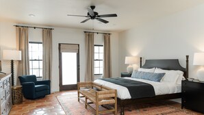 Ein Schlafzimmer mit Bett, Stuhl, Schreibtisch und Deckenventilator.