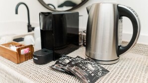 A coffee maker, a kettle, and coffee pods on a woven table. - 1 Bedroom Villa (Double Queen) (Nemo)