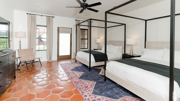 A four-poster bed with white linens, a patterned rug, and a ceiling fan. - 1 Bedroom Villa (Double Queen) (Nemo)
