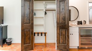 A room with a wooden wardrobe, a small table with hooks, and a tiled floor.