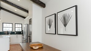 A modern kitchen with white cabinets, a wooden dining table, and two framed botanical prints on the wall. - 3 Bedroom Casita (6 Queen Beds) (Nemo)