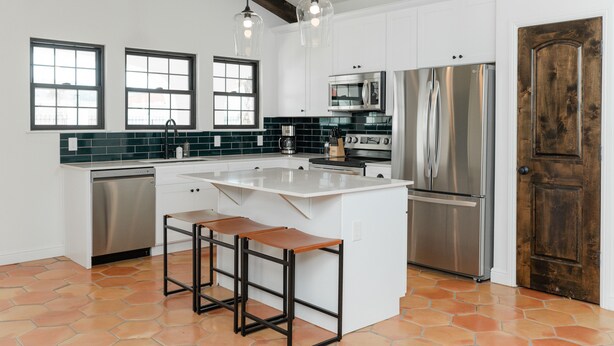 A modern kitchen with a large island, stainless steel appliances, and a rustic wooden door. - 3 Bedroom Casita (6 Queen Beds) (Nemo)