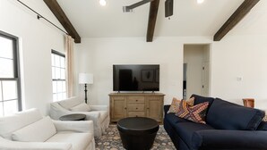 A living room with a sofa, armchair, ottoman, and a flat-screen TV on a wooden cabinet. - 3 Bedroom Casita (6 Queen Beds) (Nemo)