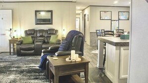 Een woonkamer met een bank, een salontafel en een eethoek met stoelen en een tafel.