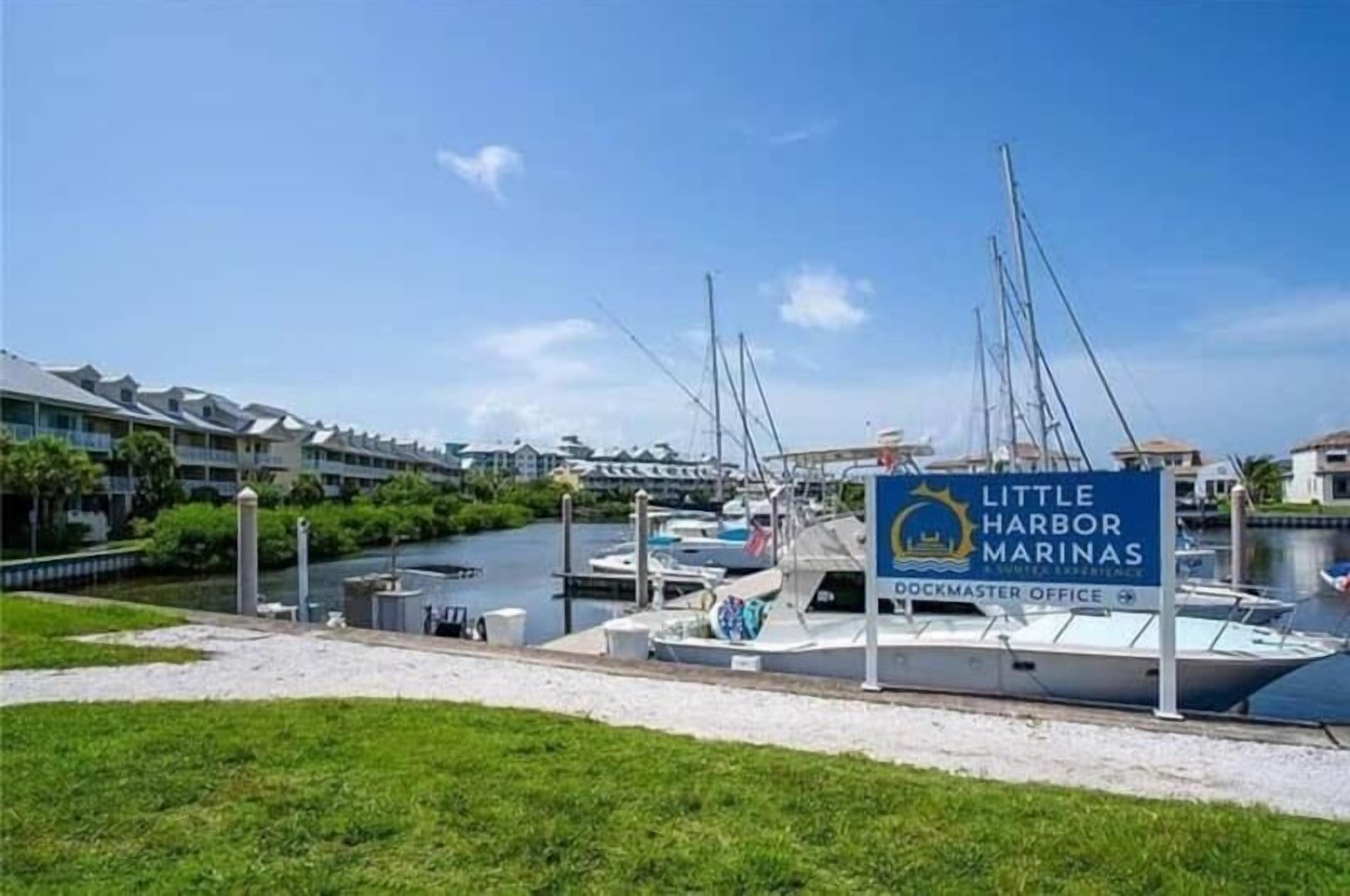 A marina with boats docked, a sign for Little Harbor Marinas, and a dockmaster office.