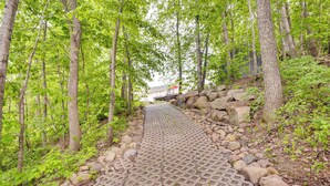 A paved pathway in a forested area with trees and rocks. - Lakefront Minnesota Vacation Rental w/ Dock (Annandale)